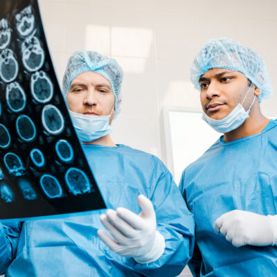 handsome doctors in uniforms and medical masks talking about x-ray in clinic