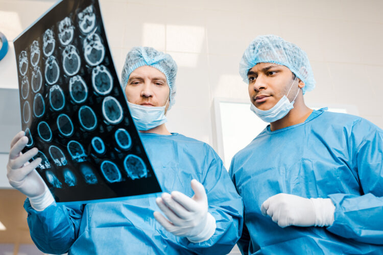 handsome doctors in uniforms and medical masks talking about x-ray in clinic